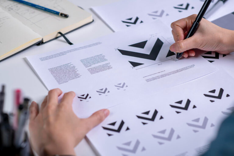 Logotipo de uma marca pessoal à mão, com estudos de proporção, cores e variações de aplicação do símbolo, processo de criação de identidade visual antes do registro no INPI.
